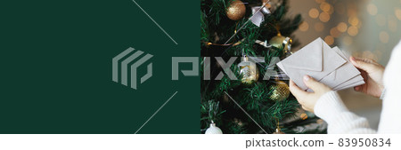 Hands holding stack of craft paper envelopes for christmas greeting card invitation design on christmas tree background with bokeh.Copy space, mock up. 83950834