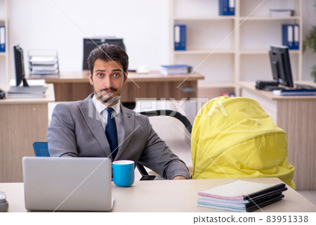 Young male employee looking after new born at workplace 83951338
