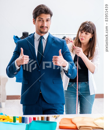 Professional tailor taking measurements for formal suit 83951439