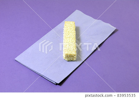White chocolate and coconut wafer cookie on lavender napkin on purple background White chocolate and coconut wafer cookie on lavender napkin on purple background 83953535