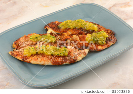 Baked tilapia fish fillets with tomato sauce, breadcrumbs and mango chutney on blue serving plate Baked tilapia fish fillets with tomato sauce, breadcrumbs and mango chutney on blue serving plate 83953826