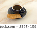Coffee biscuits and coffee in blue and white demitasse cup with saucer on table 83954159