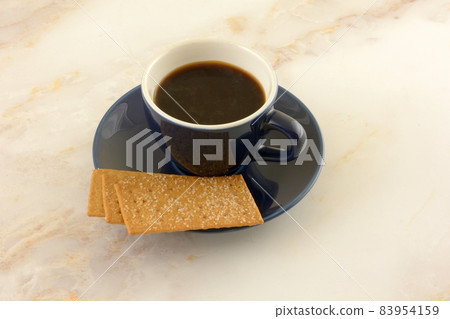 Coffee biscuits and coffee in blue and white demitasse cup with saucer on table Coffee biscuits and coffee in blue and white demitasse cup with saucer on table 83954159