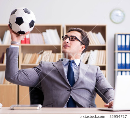 Businessman with football ball in office Businessman with football ball in office 83954717