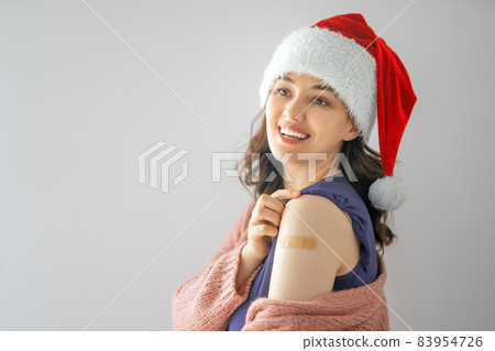 Young woman after vaccination wearing Santa hat 83954726