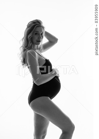 caucasian pregnant woman stroking her belly on white background. Copy space. The concept of healthy digestion, lifestyle, IVF 83955909