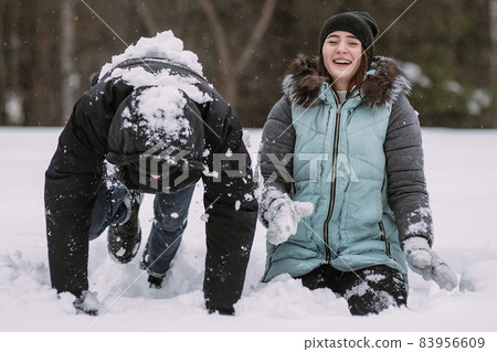 Happy couple of teenagers having fun playing in snow in winter Happy couple of teenagers having fun playing in snow in winter 83956609