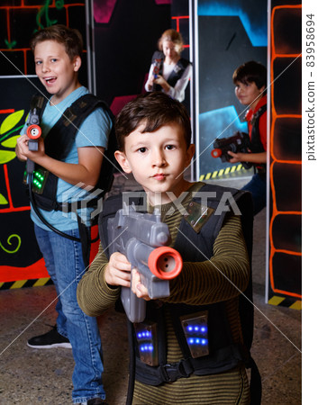 Emotional teen boy with laser pistol playing laser tag with friends on dark labyrinth Emotional teen boy with laser pistol playing laser tag with friends on dark labyrinth 83958694