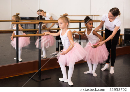 Ballet trainer teaching two little girls Ballet trainer teaching two little girls 83958702