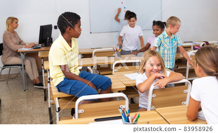 Tween boys and girls friendly talking in break in classroom Tween boys and girls friendly talking in break in classroom 83958926