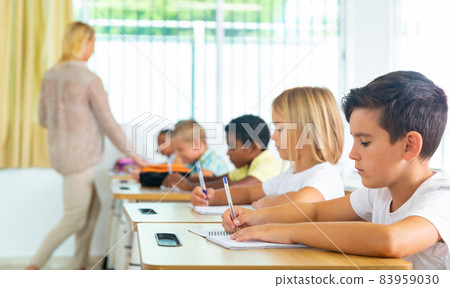Side view of schoolkids group working on lecture in classroom Side view of schoolkids group working on lecture in classroom 83959030