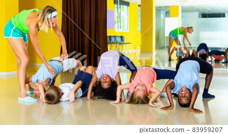 Female choreographer helping tweenagers make gymnastic bridge in Female choreographer helping tweenagers make gymnastic bridge in 83959207