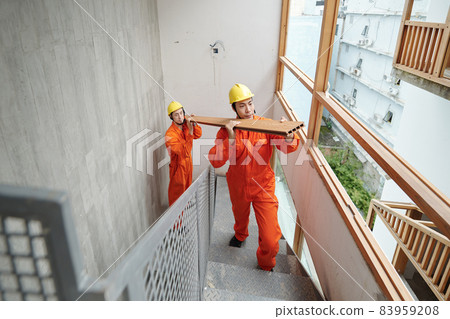 Workers Struggling Carrying Long Board Workers Struggling Carrying Long Board 83959208