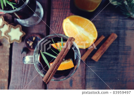 Cups with mulled wine, Christmas decorations, fir branches on a wooden background, the concept of home comfort, winter holidays celebration Cups with mulled wine, Christmas decorations, fir branches on a wooden background, the concept of home comfort, winter holidays celebration 83959497