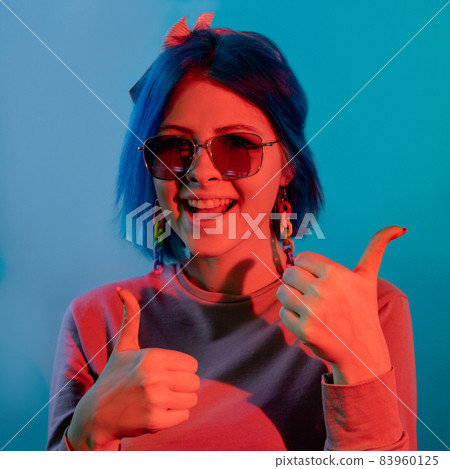 Thumbs up gesture. Approval sign. Right choice. Red neon color light happy woman showing like hand symbol isolated on blue background. 83960125