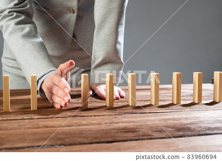 Business woman interrupting domino effect Business woman interrupting domino effect 83960694