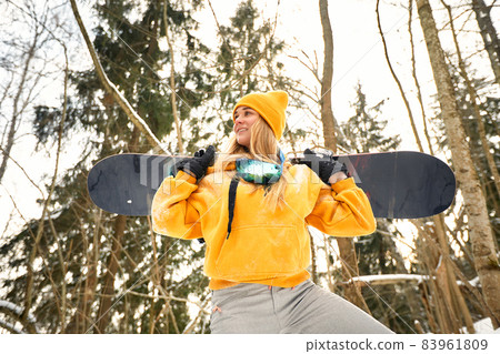 young girl or woman snowboarder goes in for winter sports in snowy forest she stands in snow and holds a snowboard young girl or woman snowboarder goes in for winter sports in snowy forest she stands in snow and holds a snowboard 83961809