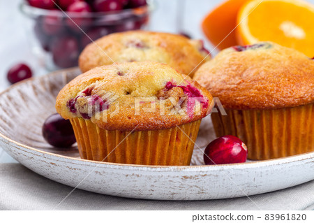 Homemade cranberry orange muffins on wooden plate, horizontal, closeup Homemade cranberry orange muffins on wooden plate, horizontal, closeup 83961820
