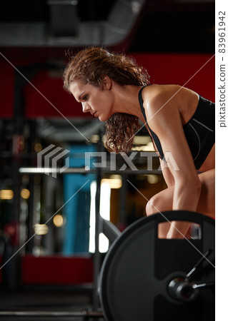 fitness woman doing exercises with dumbbell in the gym. Brunette fitness girl in black sport wear with perfect body performing biceps exercises 83961942