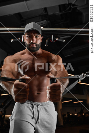 Brutal handsome Caucasian bodybuilder working out training in the gym gaining weight pumping up muscles and poses fitness and bodybuilding concept 83962131