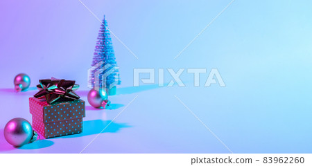 Christmas composition neon. Holiday decoration bauble ball on neon gradient backdrop. Minimal abstract tree, xmas gift box. New year banner. 83962260
