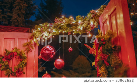 Beautiful house decorated for Christmas is about Christmas trees. Open the door of the house for Santa Claus. Christmas night. Christmas holiday wreath adorns front door to home. Beautiful house decorated for Christmas is about Christmas trees. Open the door of the house for Santa Claus. Christmas night. Christmas holiday wreath adorns front door to home. 83962688
