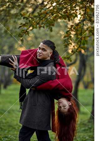 Young couple in love walking in the autumn park holding hands looking in the sunset 83962706