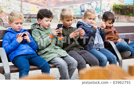 Children on bench with phones 83962791