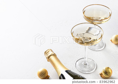 Festive New Year champagne and Christmas gold baubles on white background. 83962962
