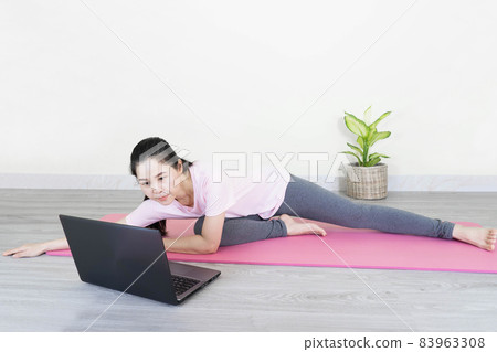 Girl doing yoga at home. Yoga online on the laptop. Healthy lifestyle and home yoga concept.Portrait of healthy young Asian woman practicing yoga exercises and learning online on laptop at home. Girl doing yoga at home. Yoga online on the laptop. Healthy lifestyle and home yoga concept.Portrait of healthy young Asian woman practicing yoga exercises and learning online on laptop at home. 83963308