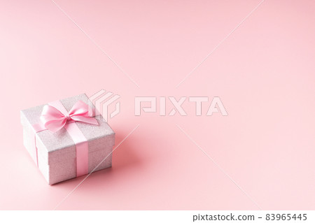 Silver glitter gift box with pink ribbon bow on pink background. Christmas, Valentine's day or birthday concept. Silver glitter gift box with pink ribbon bow on pink background. Christmas, Valentine's day or birthday concept. 83965445