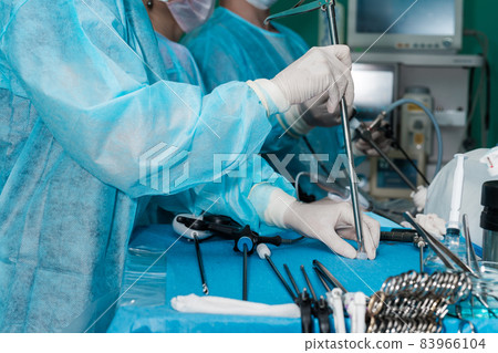 The surgeon holds a surgical laparoscopic manipulator in his hands. 83966104