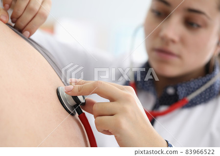 Young female doctor listen to patients back with stethoscope tool Young female doctor listen to patients back with stethoscope tool 83966522