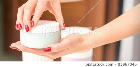 The woman opens the lid holding a jar of moisturizing cream, mockup, copy space, closeup. 83967040