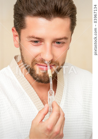 Young caucasian man receiving nasal inhalation Maholda with essential oil in the nose at a hospital. 83967134