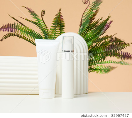 white plastic tube and bottle for cosmetics on a white table. Packaging for cream, gel, serum, advertising and product promotion, mock up white plastic tube and bottle for cosmetics on a white table. Packaging for cream, gel, serum, advertising and product promotion, mock up 83967427