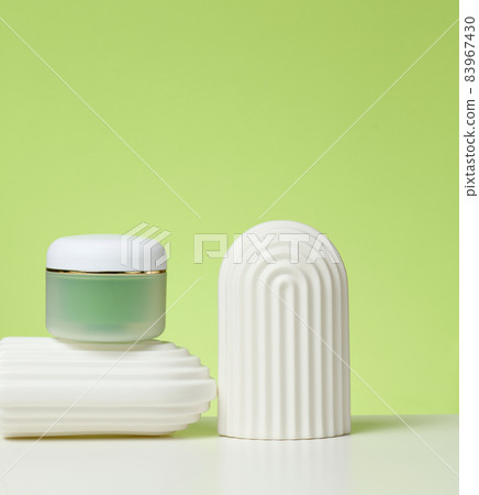 green jar for cosmetics on a white table. Packaging for cream, gel, serum, advertising and product promotion, mock up 83967430