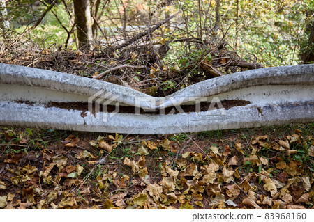 Dirty guardrail in the mountains, which seems to be dented by a fallen tree Dirty guardrail in the mountains, which seems to be dented by a fallen tree 83968160