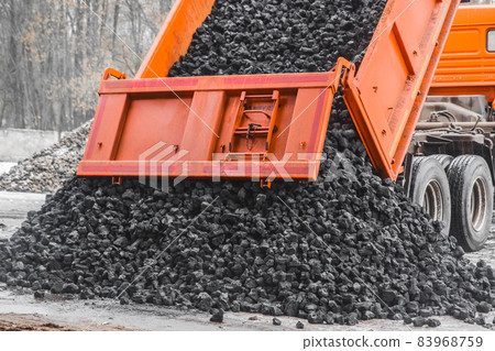 Dump truck in the industrial zone unloads coking coal from the body Dump truck in the industrial zone unloads coking coal from the body 83968759
