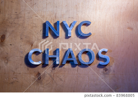 The words NYC chaos laid with metal letters on flat plywood surface under white and blue police lights. Concept. 83968805