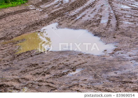 puddle in dirt road at summer daylight - closeup with selective focus, diagonal composition puddle in dirt road at summer daylight - closeup with selective focus, diagonal composition 83969054