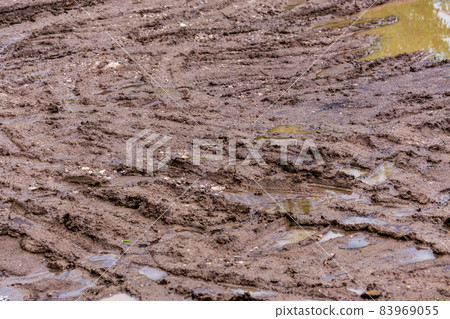 dirty clay mud road with puddles and tire tracks - closeup with selective focus and blur dirty clay mud road with puddles and tire tracks - closeup with selective focus and blur 83969055