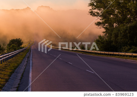 dense early morning fog in wold at summer highway near river with guard rails dense early morning fog in wold at summer highway near river with guard rails 83969123