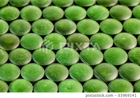 close-up background of many green organic spirulina tablets laid tight in one layer on flat surface 83969141