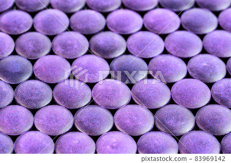 close-up background of many purple organic compacted powder tablets laid tight in one layer on flat surface 83969142