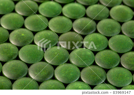close-up background of many green organic spirulina tablets laid tight in one layer on flat surface 83969147