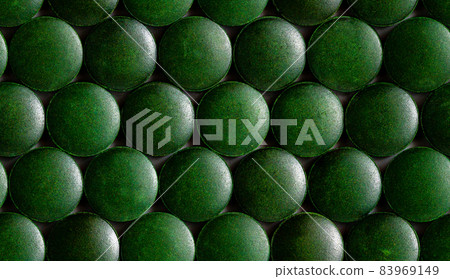 a seamless hexagonal pattern of many green organic spirulina tablets laid tight in one layer on flat surface 83969149