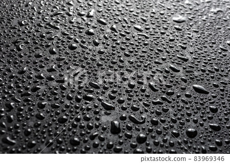 close-up view of water drops on black hydrophobic surface macro sith selective cous and background blur 83969346