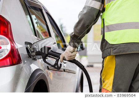 hand in white cotton fabric glove refueling gray metallic car on gas station - close-up with selective focus hand in white cotton fabric glove refueling gray metallic car on gas station - close-up with selective focus 83969504