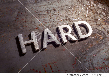 the word hard laid with silver metal letters on rusted burnt iron flat surface background the word hard laid with silver metal letters on rusted burnt iron flat surface background 83969550